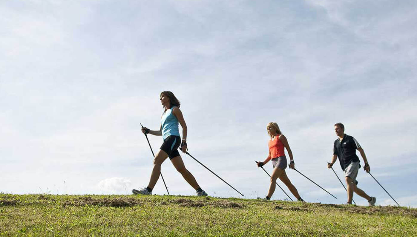 Menschen beim Nordic Walking vor einem blauen Himmel